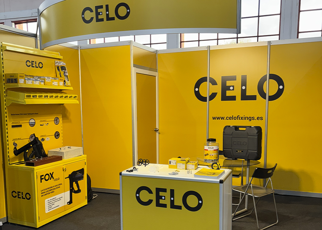 Stand de CELO en la feria ADIP con mostrador amarillo con una pistola de clavos FOX y otros productos