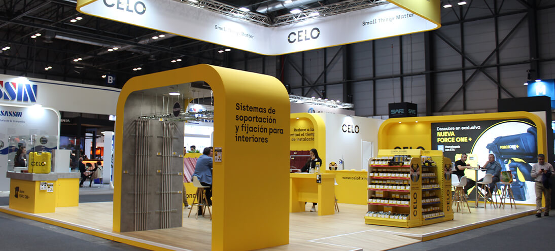 Stand de CELO en la feria Matelec con estructura y mobiliario amarillo y expositores de productos de fijación y suportación
