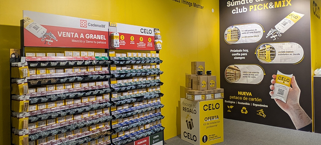 Stand de CELO en la feria C&R con estructura y mostradores amarillos y expositores de productos de fijación y suportación