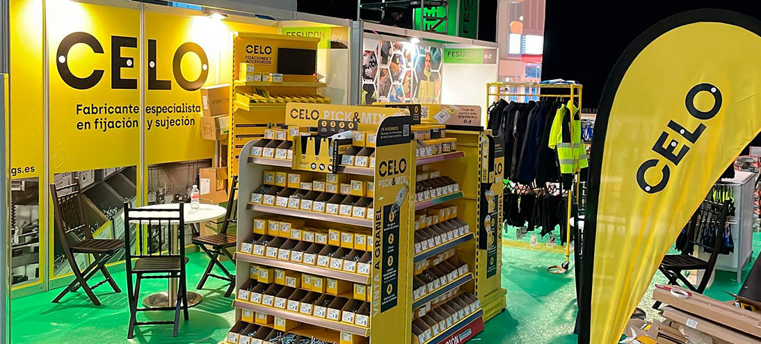 Stand de CELO en la feria Matelec con estructura y mobiliario amarillo y expositores de productos de fijación y suportación